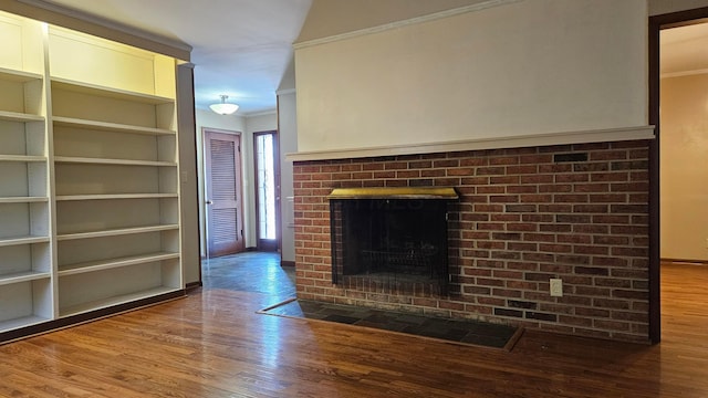 unfurnished living room featuring built in shelves, crown molding, a fireplace, and hardwood / wood-style flooring