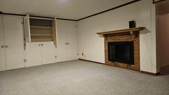 unfurnished living room featuring a brick fireplace, ornamental molding, carpet flooring, and wooden walls