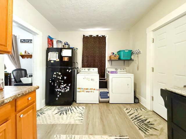 washroom featuring light wood-type flooring, cabinets, a textured ceiling, and washer and dryer