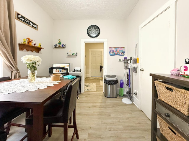 dining room featuring light wood-type flooring and a textured ceiling