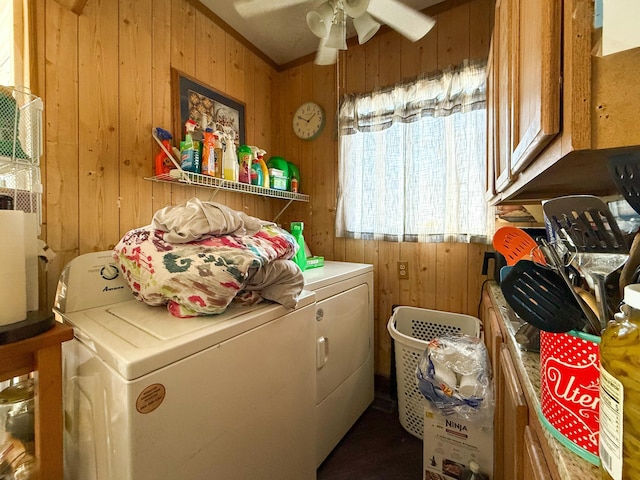 laundry area with ceiling fan, cabinets, washer and clothes dryer, and wood walls