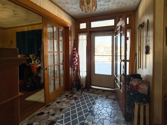 entryway featuring french doors, wood walls, and crown molding