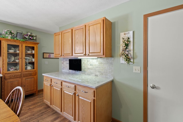 kitchen featuring light stone counters, a textured ceiling, dark hardwood / wood-style flooring, and tasteful backsplash