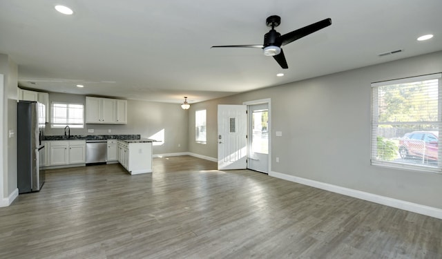 unfurnished living room with hardwood / wood-style floors, ceiling fan, and sink