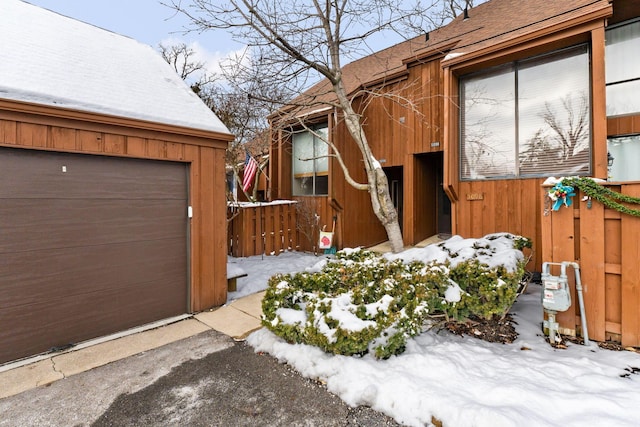 snow covered property with a garage