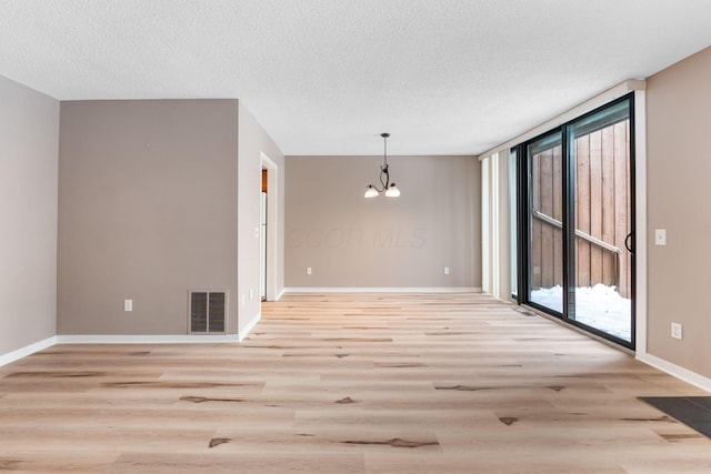 unfurnished room with a wall of windows, light wood-type flooring, a chandelier, and a textured ceiling