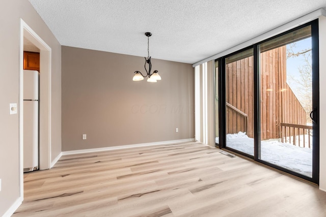 unfurnished dining area featuring light hardwood / wood-style floors, a textured ceiling, expansive windows, and a chandelier