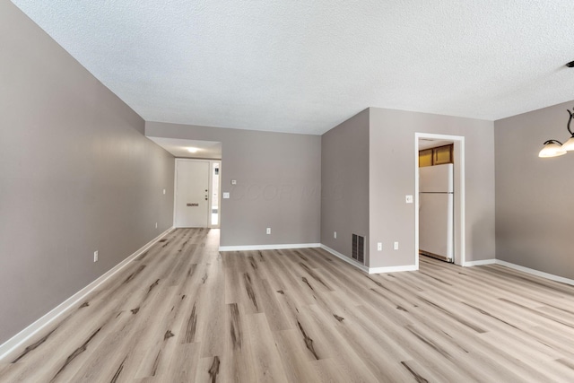 unfurnished living room with a textured ceiling and light hardwood / wood-style floors