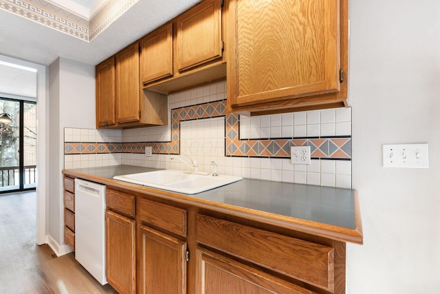 kitchen featuring tasteful backsplash, light wood-type flooring, dishwasher, and sink