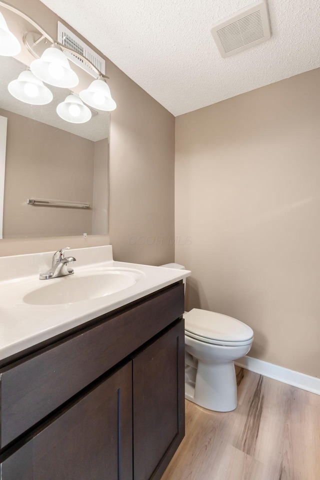 bathroom featuring a textured ceiling, toilet, vanity, and hardwood / wood-style floors