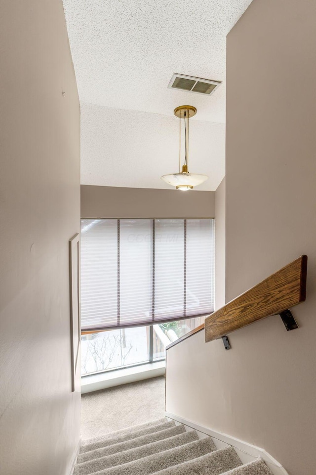 stairs with a textured ceiling and carpet