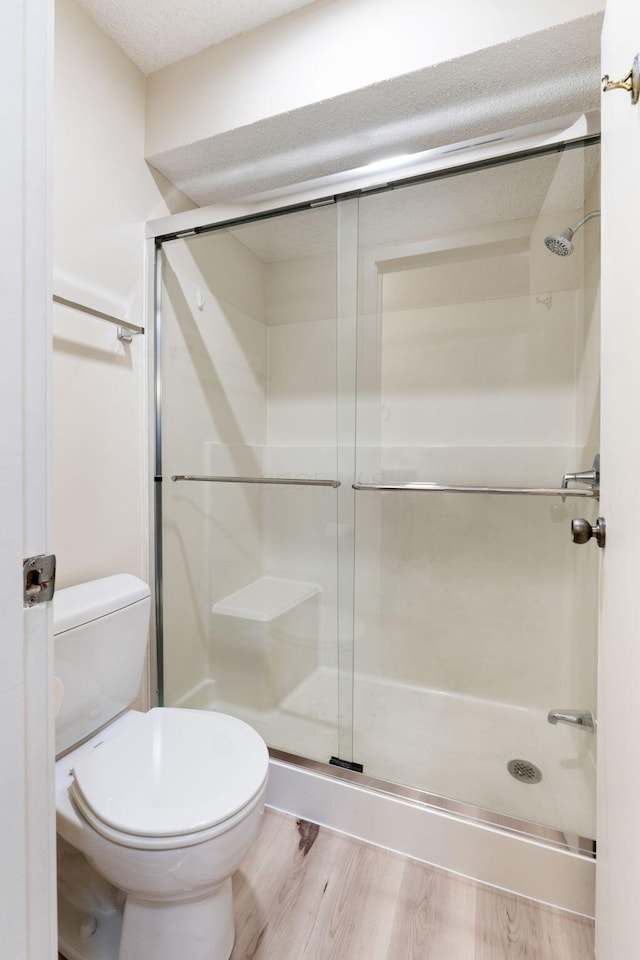 bathroom featuring toilet, wood-type flooring, and an enclosed shower