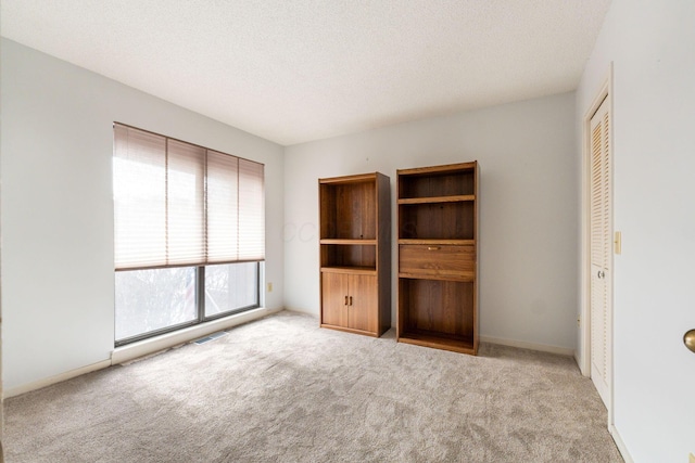 unfurnished bedroom with light carpet, a closet, and a textured ceiling