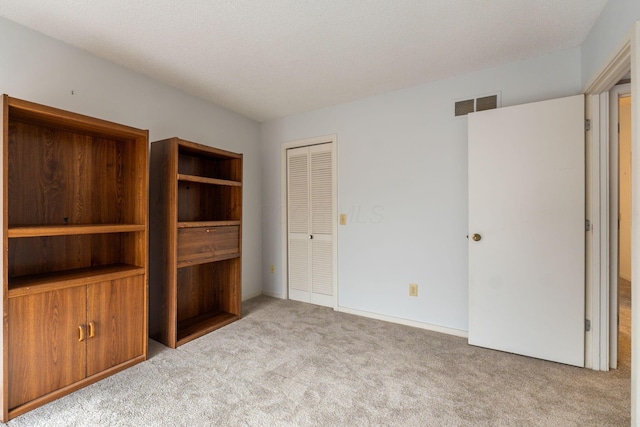 unfurnished bedroom featuring light colored carpet and a closet