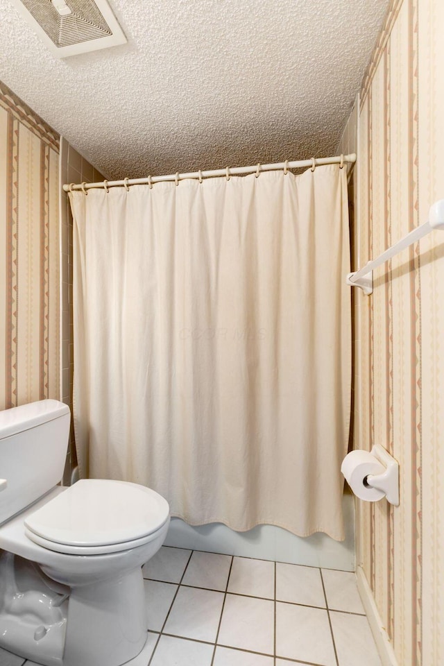 bathroom featuring toilet, tile patterned flooring, and a textured ceiling