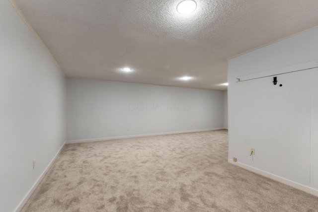 empty room featuring a textured ceiling, ornamental molding, and light colored carpet