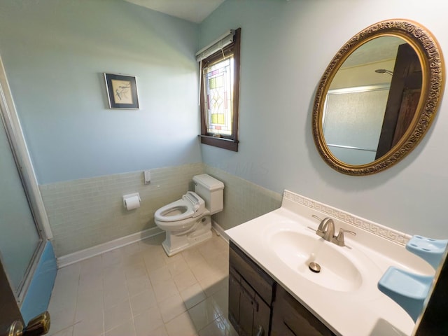 bathroom with toilet, walk in shower, vanity, tile patterned floors, and tile walls