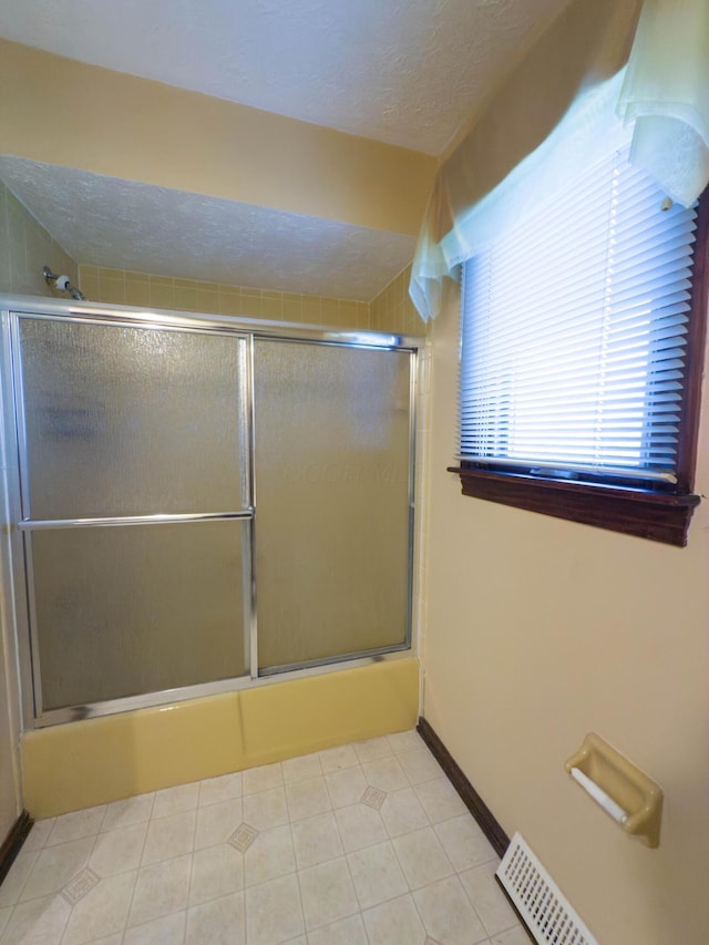 bathroom with tile patterned flooring and combined bath / shower with glass door