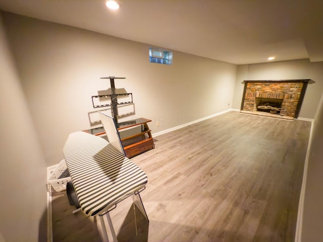 sitting room featuring wood-type flooring and a brick fireplace