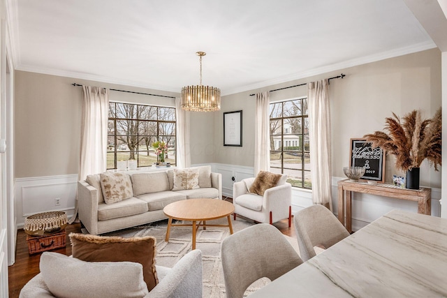 living room with an inviting chandelier, hardwood / wood-style floors, and ornamental molding