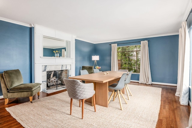 dining space featuring a premium fireplace, ornamental molding, and hardwood / wood-style floors