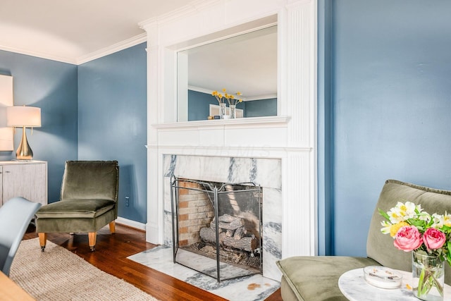 sitting room with ornamental molding, a high end fireplace, and dark hardwood / wood-style flooring