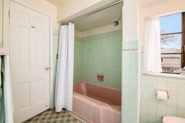 bathroom featuring tile walls and shower / bathtub combination with curtain