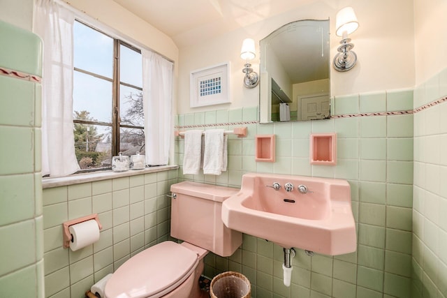 bathroom featuring toilet, sink, and tile walls