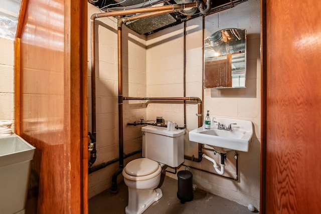 bathroom featuring sink, concrete flooring, and toilet