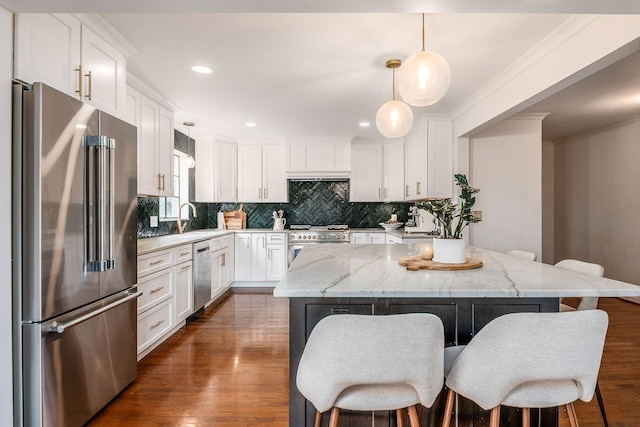 kitchen featuring a kitchen island, pendant lighting, high quality appliances, white cabinetry, and light stone countertops