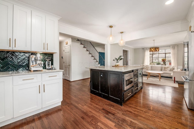 kitchen featuring pendant lighting, white cabinets, dark hardwood / wood-style flooring, a center island, and crown molding