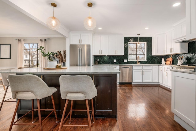 kitchen featuring pendant lighting, white cabinets, a kitchen breakfast bar, a center island, and stainless steel appliances