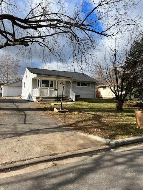 view of front of property featuring a porch, an outbuilding, a front yard, and a garage