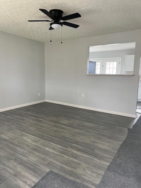 empty room featuring dark hardwood / wood-style flooring, a textured ceiling, and ceiling fan