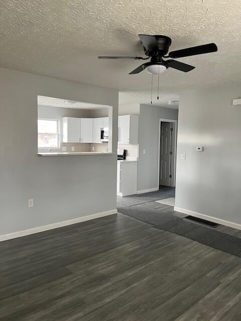 unfurnished living room featuring a textured ceiling, ceiling fan, and dark hardwood / wood-style floors