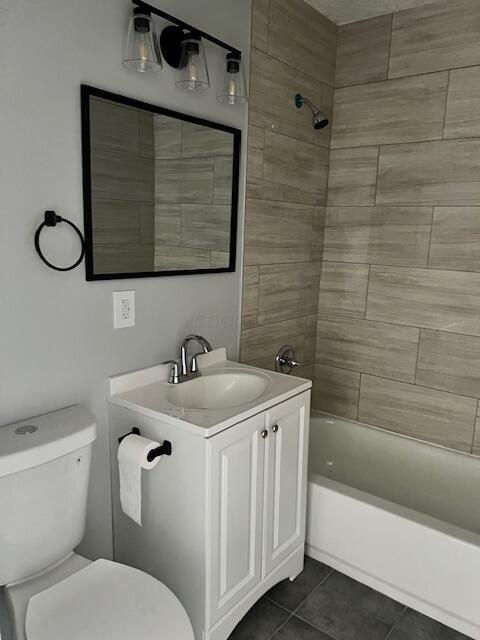 full bathroom with toilet, vanity, tile patterned floors, and tiled shower / bath combo