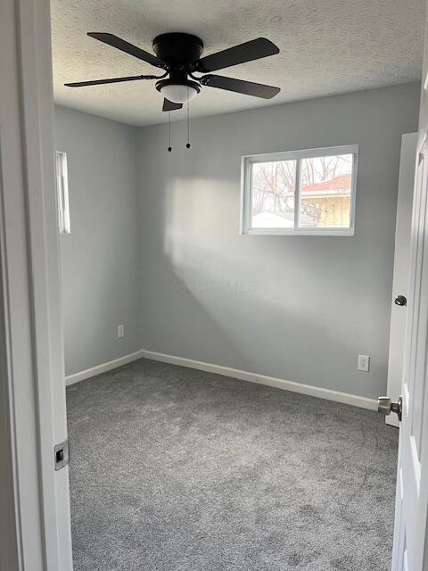 unfurnished room with a textured ceiling, light carpet, and ceiling fan