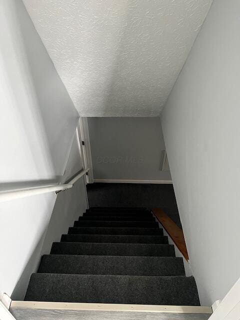 stairway featuring a textured ceiling