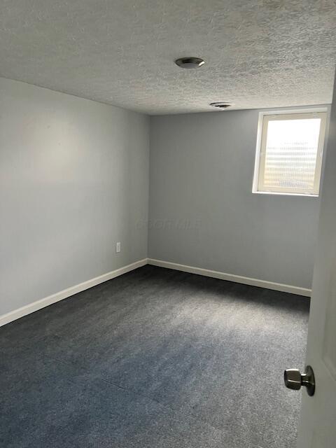 carpeted empty room with a textured ceiling