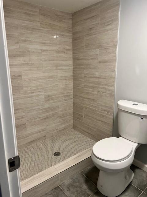 bathroom featuring tiled shower, tile patterned floors, and toilet