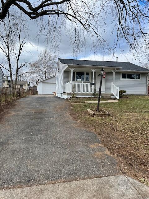 view of front of house featuring a porch, a front yard, a garage, and an outdoor structure