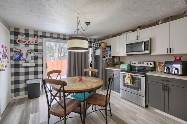 kitchen featuring light wood-type flooring, a textured ceiling, appliances with stainless steel finishes, and light countertops