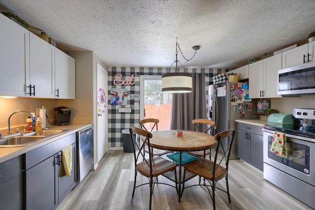 kitchen with a sink, light wood-type flooring, appliances with stainless steel finishes, and light countertops