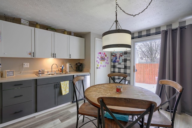 kitchen featuring gray cabinets, a sink, light countertops, dishwasher, and light wood-type flooring