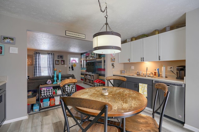 dining space with light wood finished floors, a textured ceiling, and baseboards