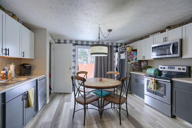 kitchen with a sink, light wood-style floors, appliances with stainless steel finishes, and light countertops