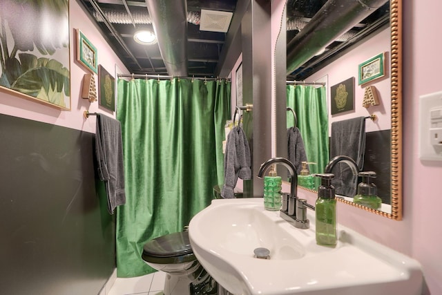 bathroom with a sink, curtained shower, and toilet