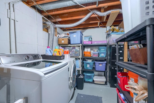 laundry area featuring concrete block wall, laundry area, and washing machine and clothes dryer