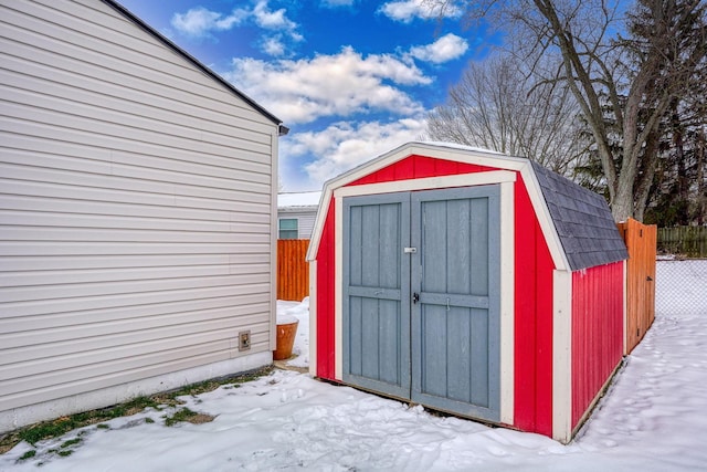 snow covered structure with a storage unit, an outdoor structure, and fence