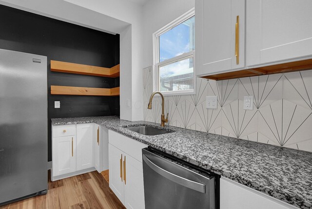 262 N 17th St, Columbus, OH 43203 - kitchen with stainless steel appliances, light stone countertops, decorative backsplash, sink, and white cabinetry